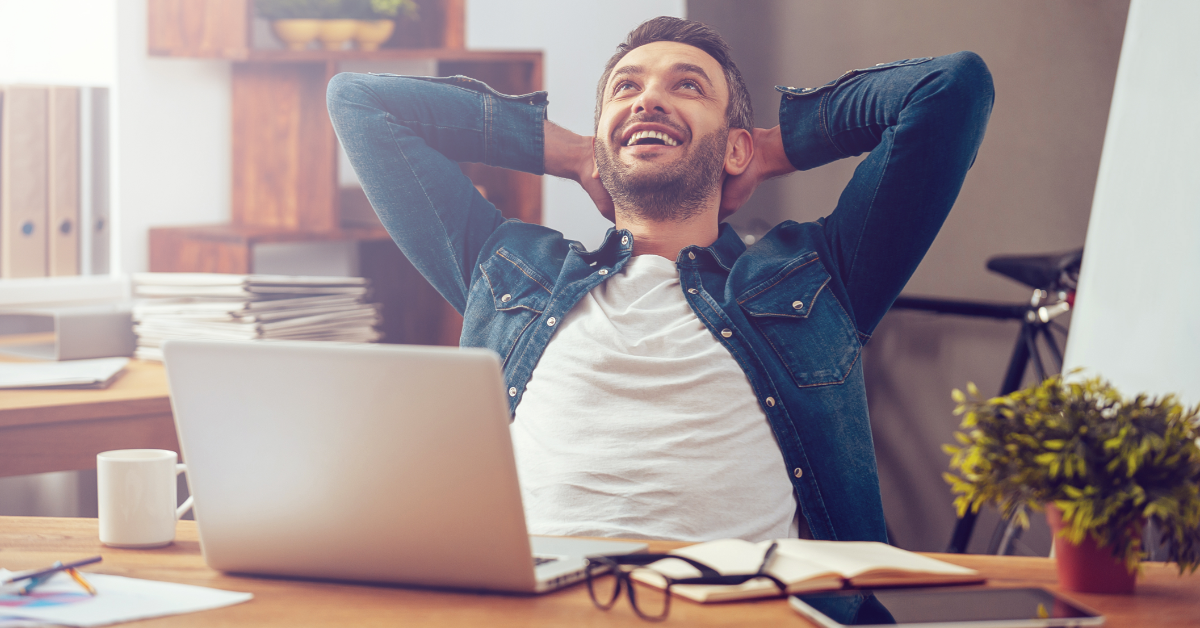 man relaxing and leaning back in an office chair with his hands on his head