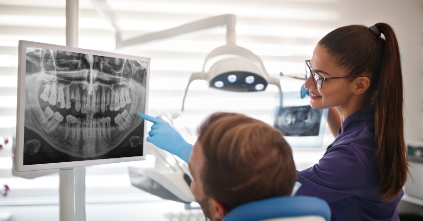 Figure 1. Woman showing patient a dental x-ray of their teeth