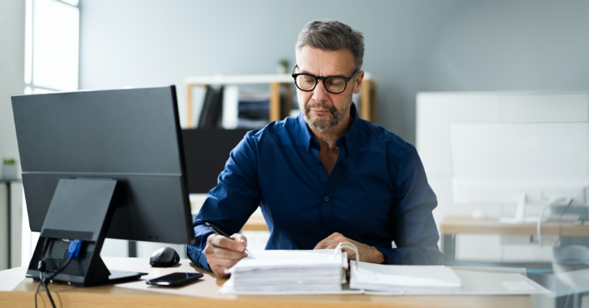 Man at a desk writing in notebook